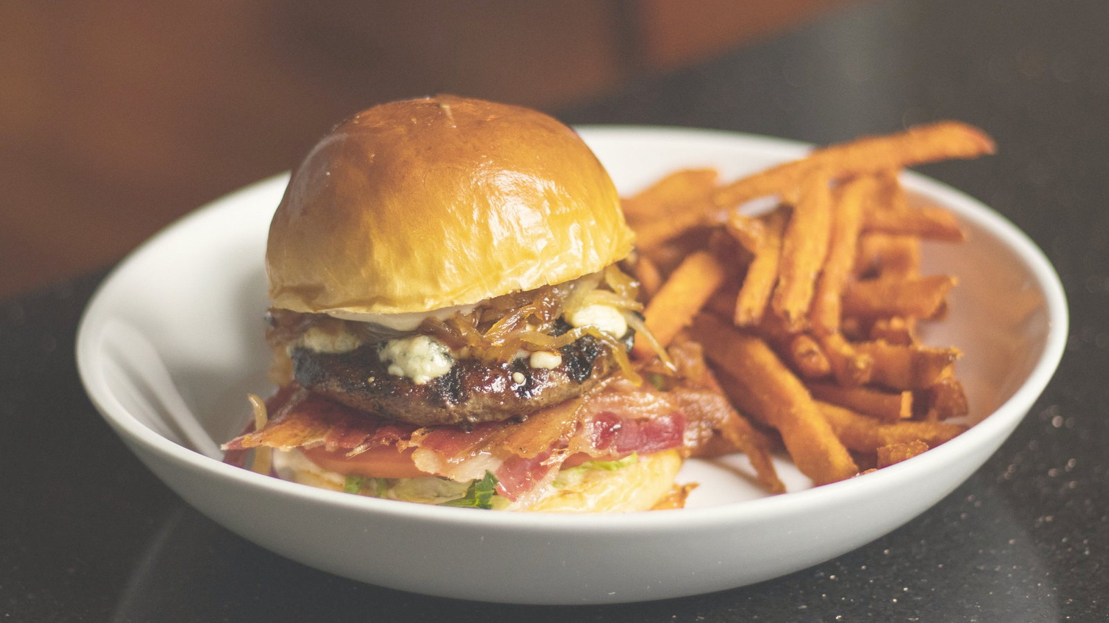 Burger and sweet-potato fries, glossy brioche and caramelized onion.