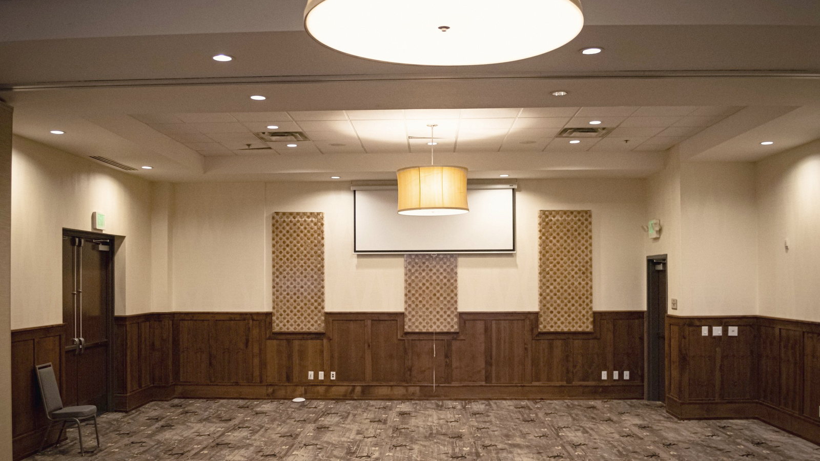A second private room, deliberately empty, with wainscot panelling and drum pendants.